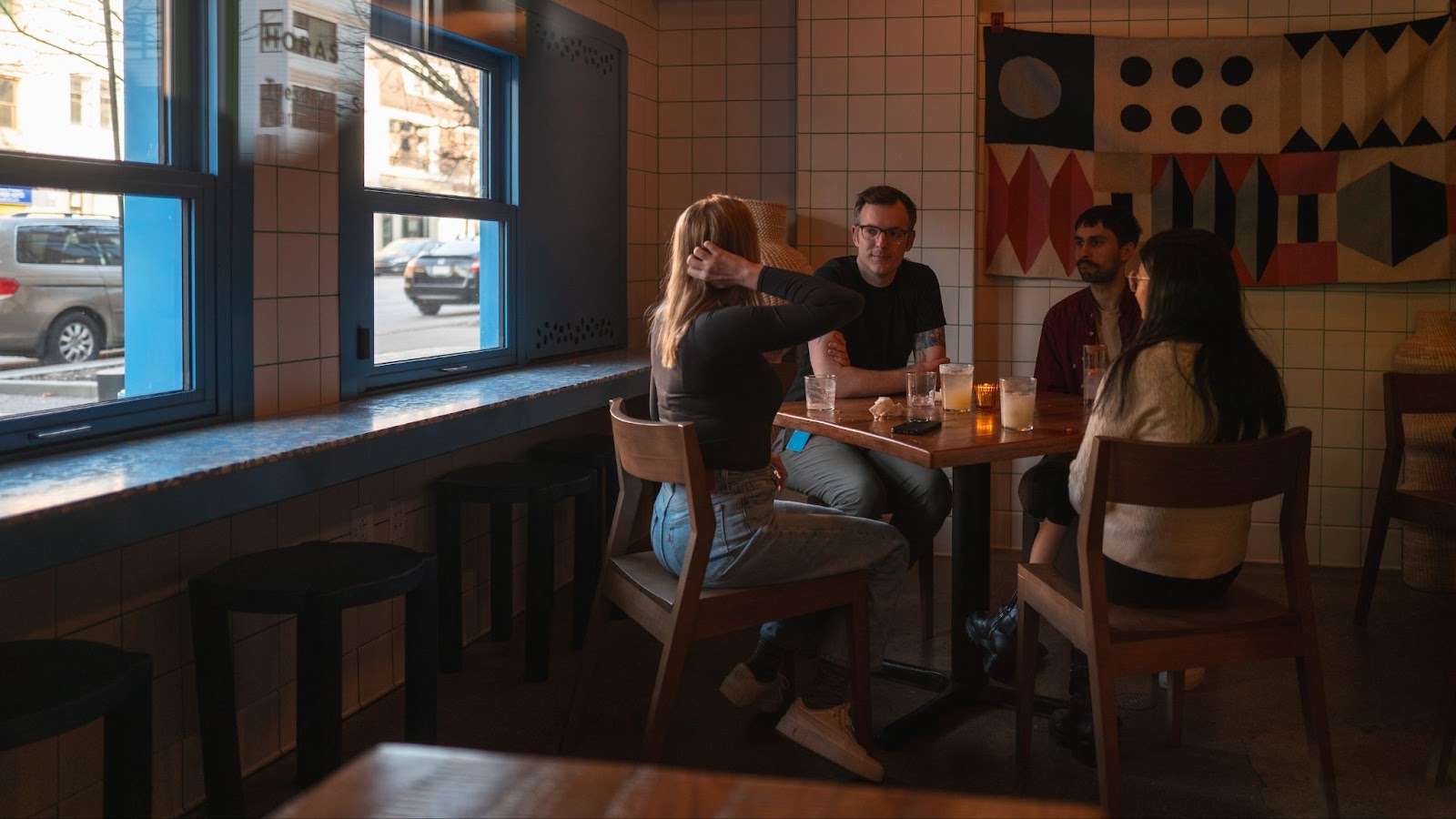 Diners sitting at a table at Duolingo's Taqueria, with a colorful tapestry behind them. 